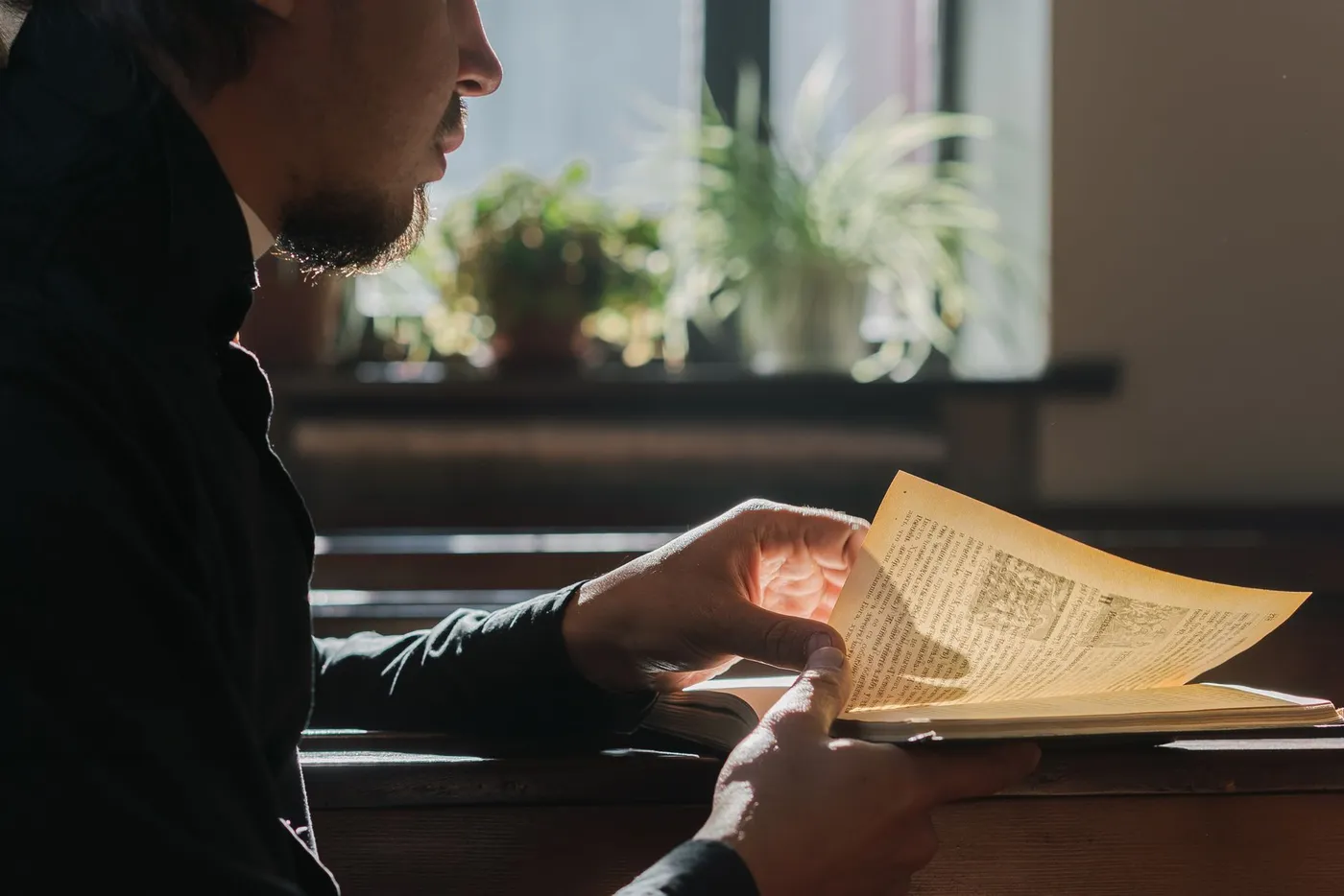 A man reading a religious book by a window