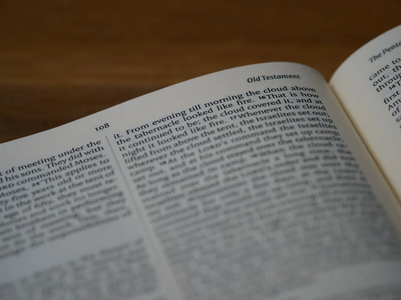 An open Bible resting on a wooden surface, an Old Testament page in shallow focus