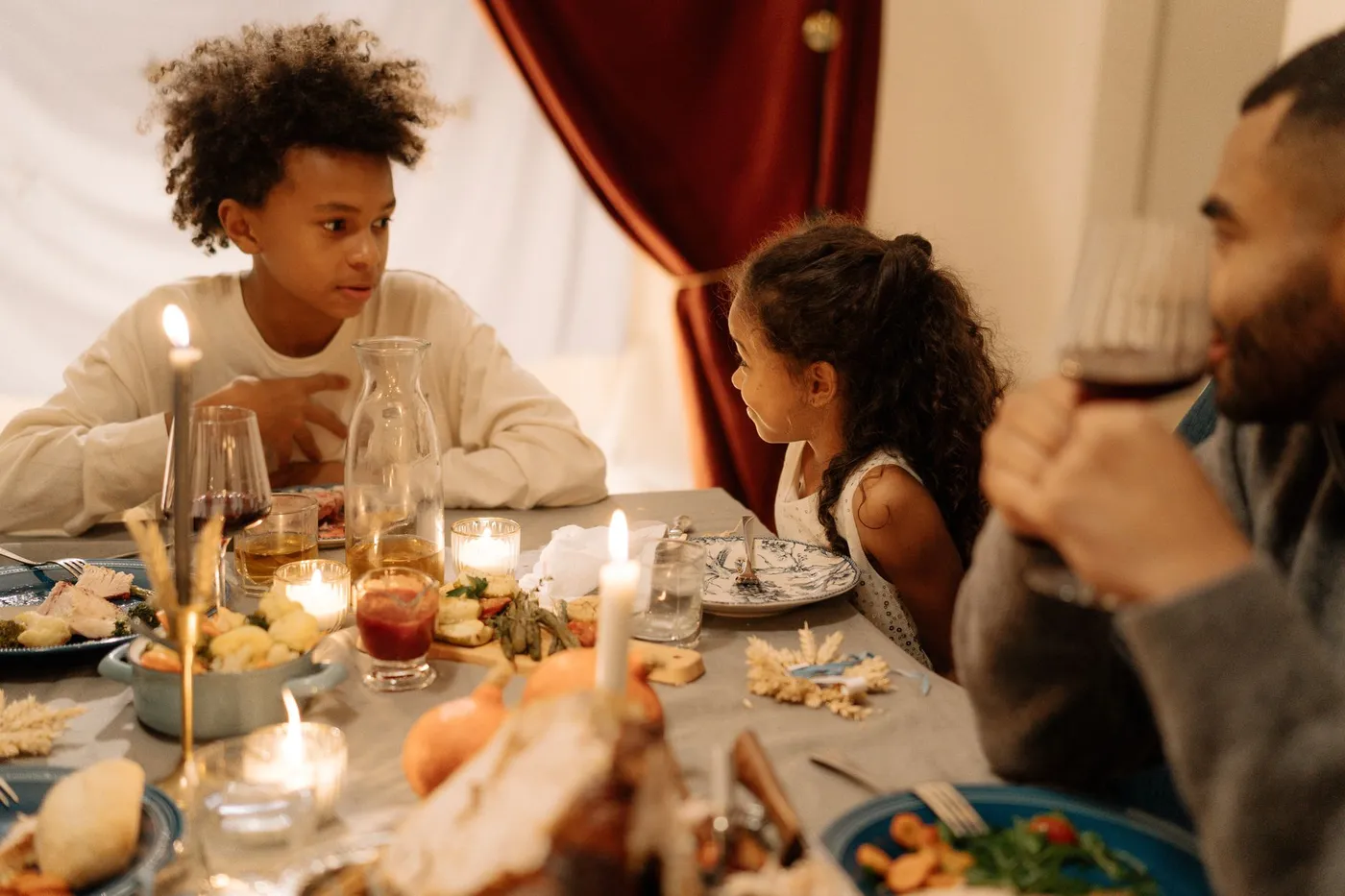 A family talking around a candlelit Thanksgiving table set with food