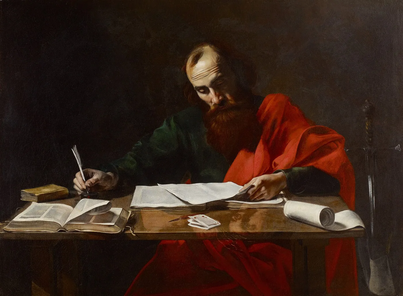 A painting of the apostle Paul at a wooden table, quill in hand, reading a sheet of paper, with an open book, a rolled scroll and a sword beside him