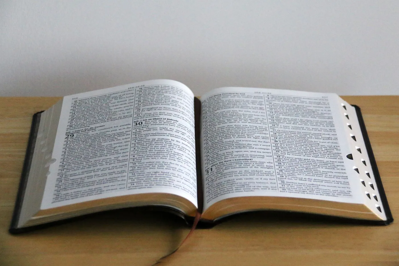 An open Bible lying on a wooden table in daylight