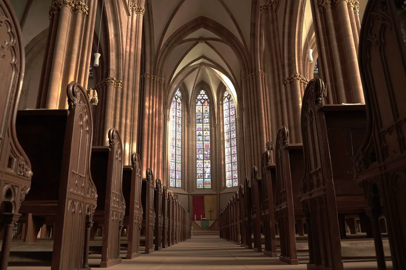 Rows of brown wooden pews inside a cathedral